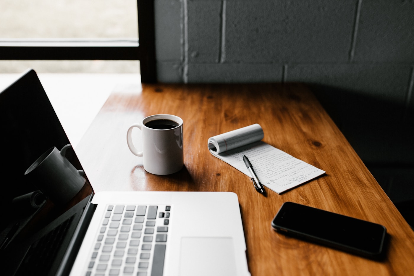 A notebook, coffee, and laptop on a wooden table
