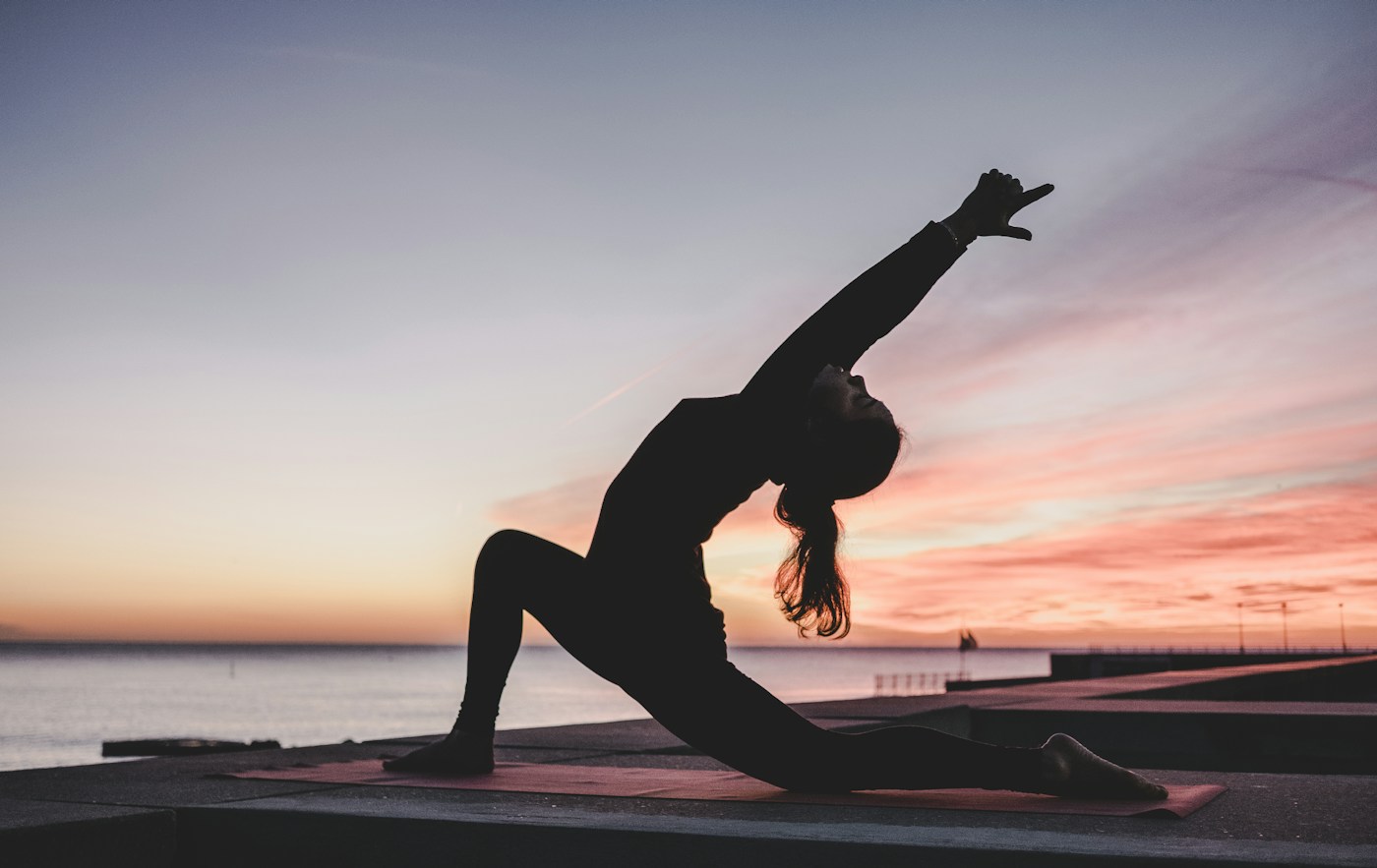 Yoga on a mat by the water at sunset